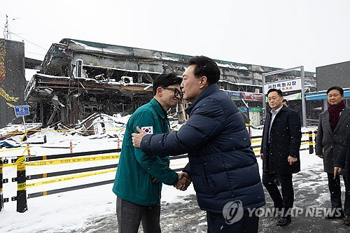 윤석열 대통령이 23일 충남 서천군 서천읍 서천특화시장 화재 현장에서 국민의힘 한동훈 비상대책위원장과 만나 악수하고 있다. 대통령실 제공